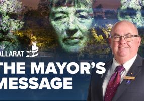 Text with The Mayor's Message with an image of Mayor Cr Des Hudson in front of the 'Monuments' exhibition by Craig Walsh which is set to light up Sturt Street