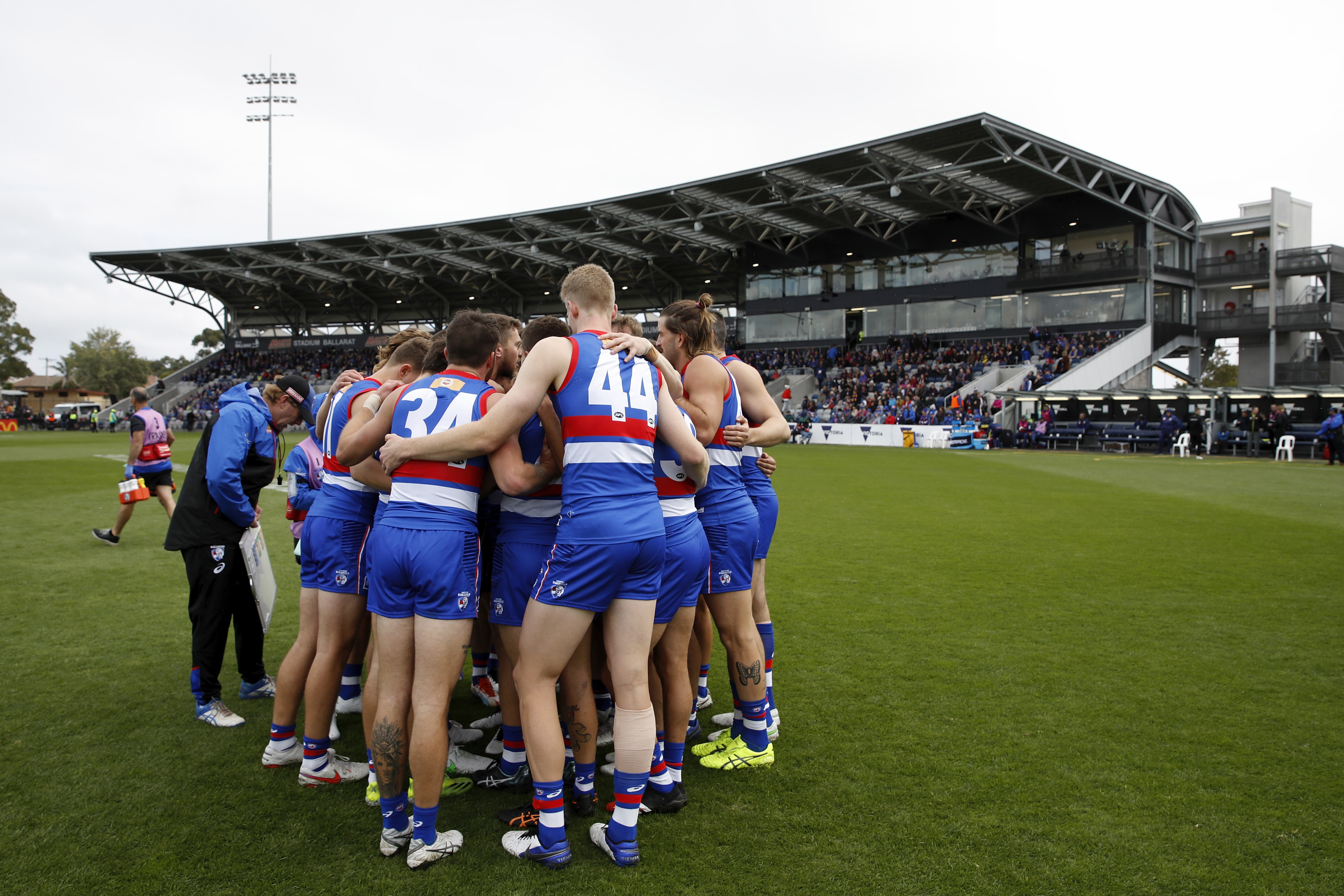 Western Bulldogs AFL players huddle before the start of a game at Mars Stadium