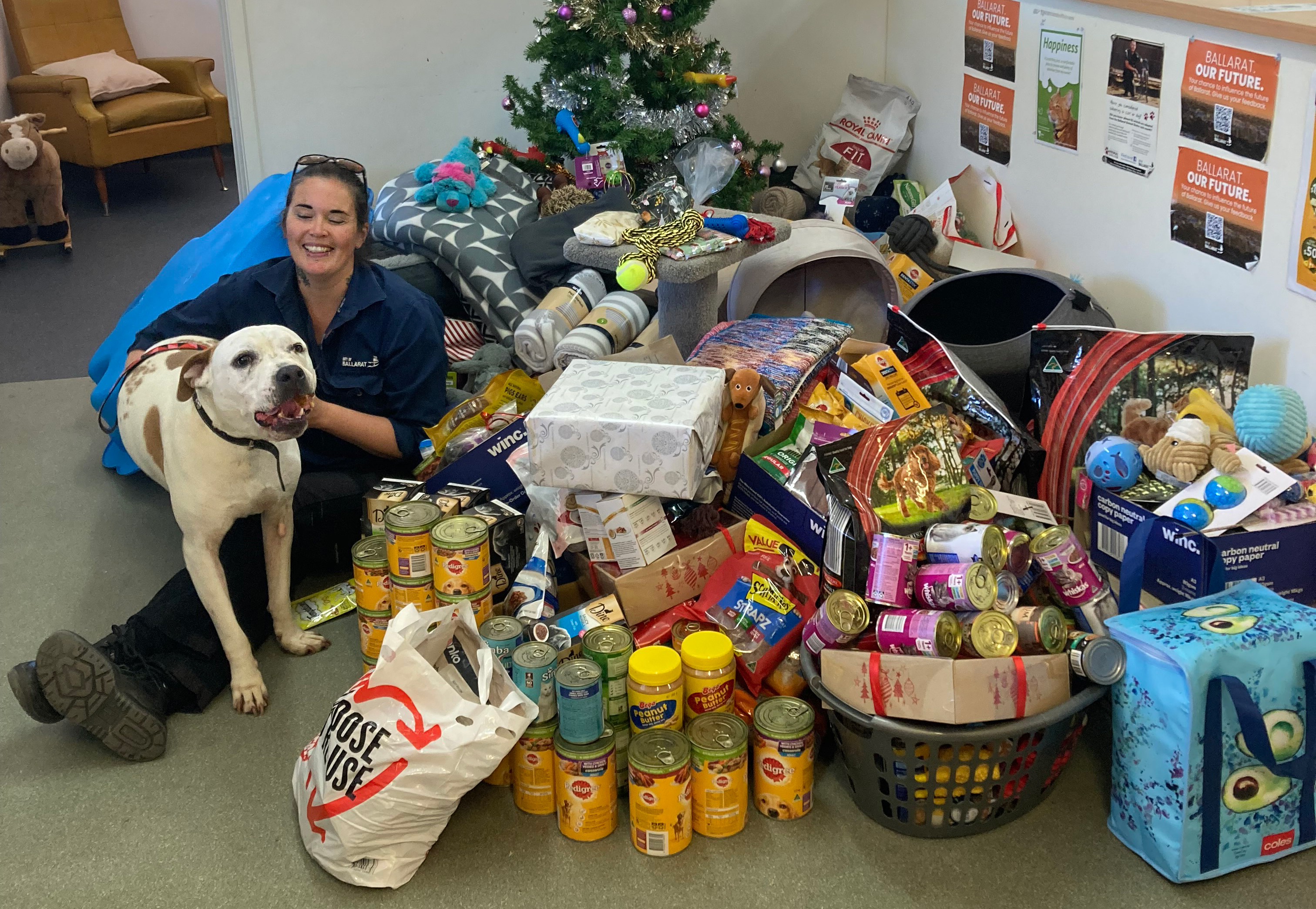 Animal shelter worker with dog and donations of food and pet toys