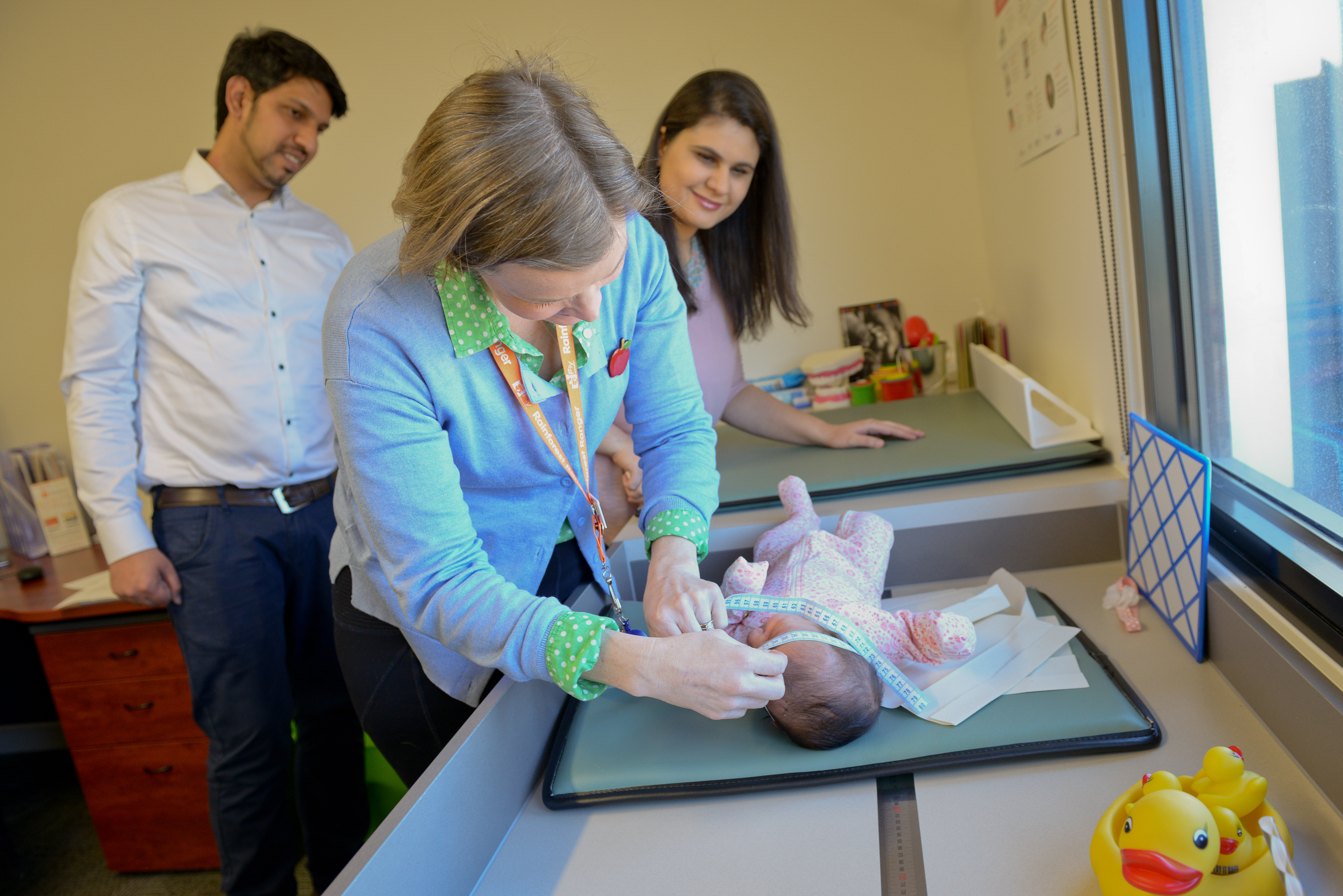 A maternal and child health nurse attends to an infant with parents nearby