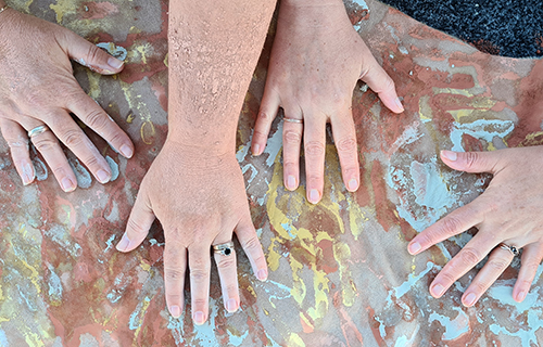 Four hand on a rock with painted hand prints underneath