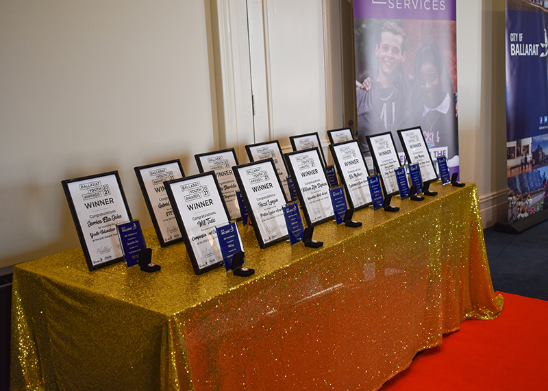 Award certificates lined up on a gold table