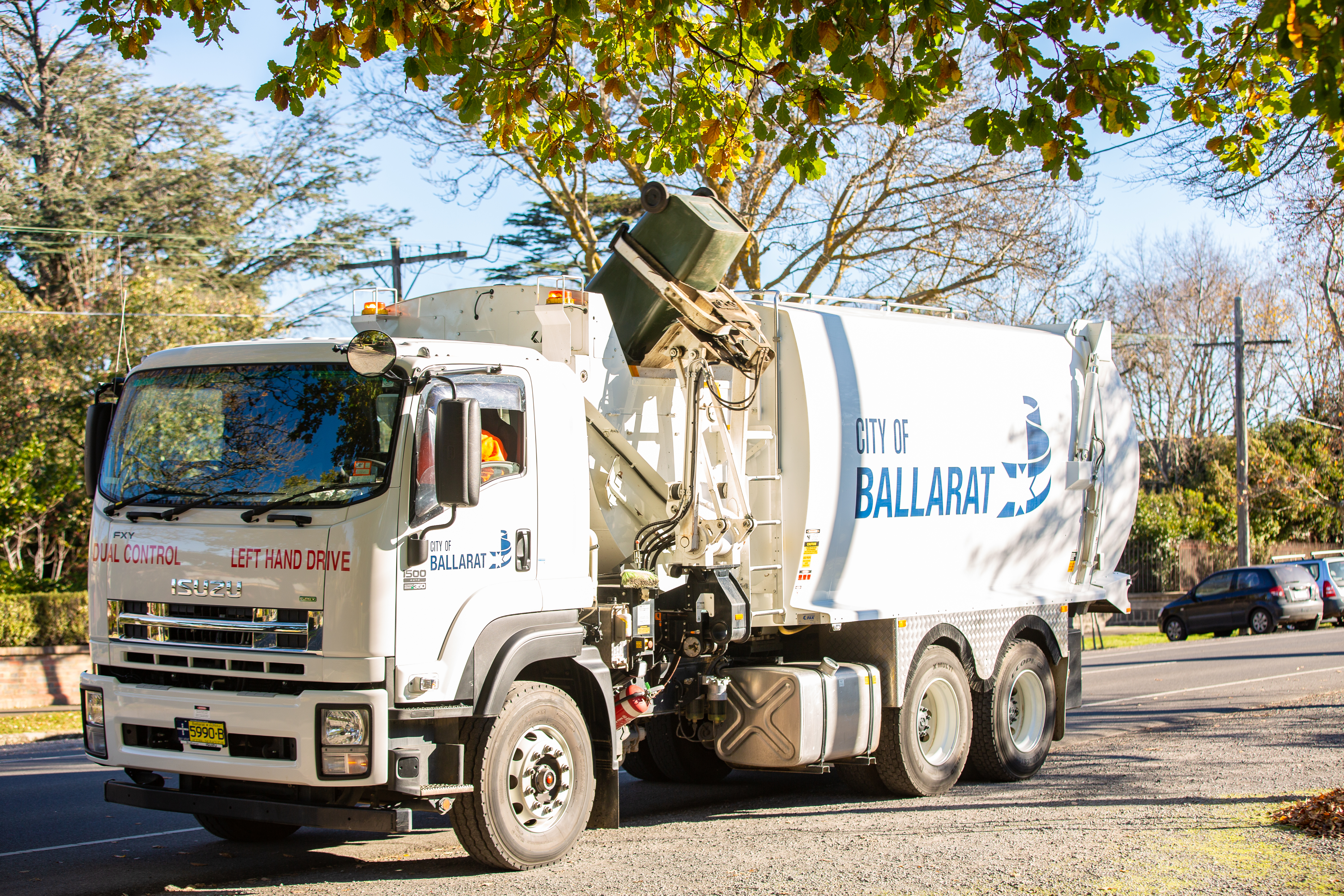 A waste truck lifts a bin, preparing to empty it. 