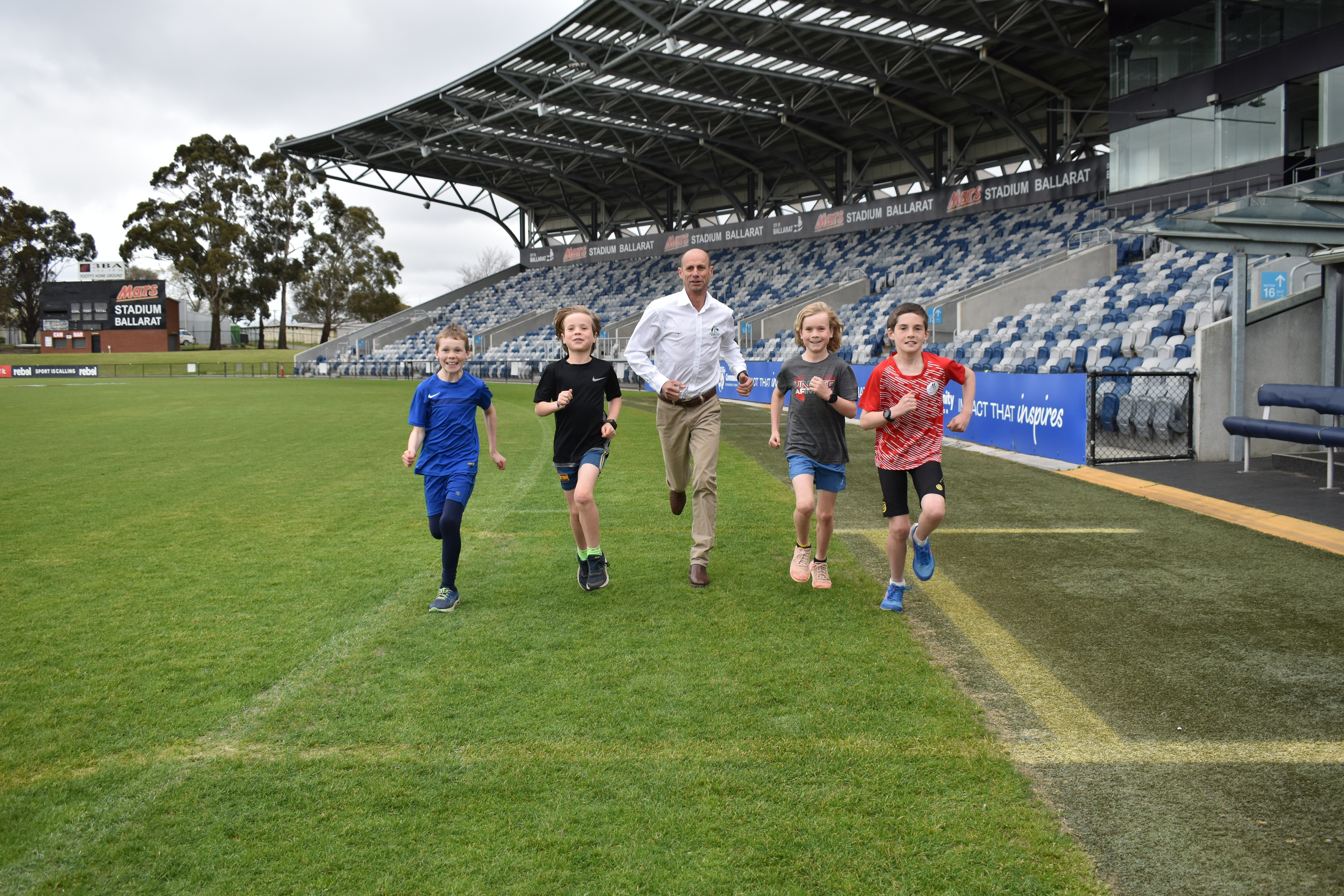 Generic photo children running with Steve Moneghetti at Mars Stadium