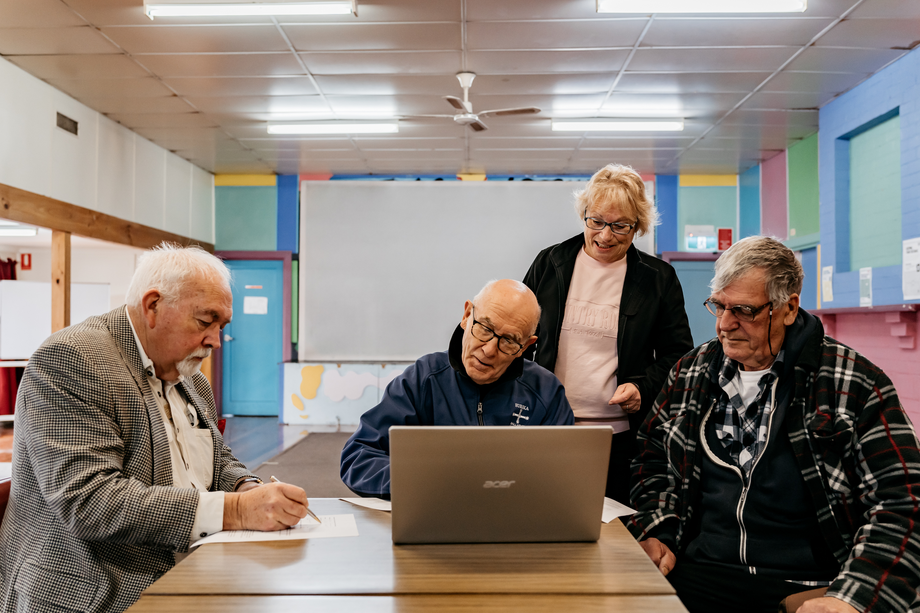 Generic photo group of people around a table working on a computer