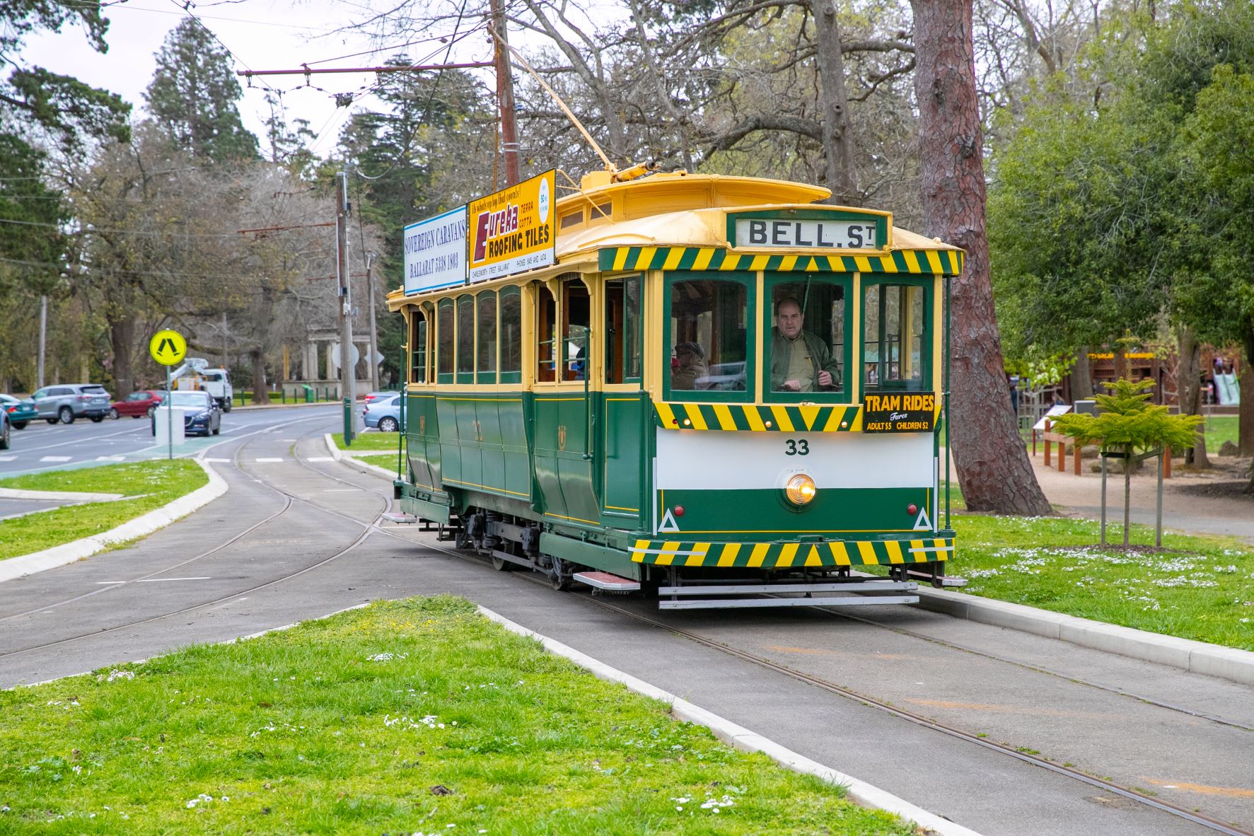 Green and yellow tram on the tracks near Lake Wendouree
