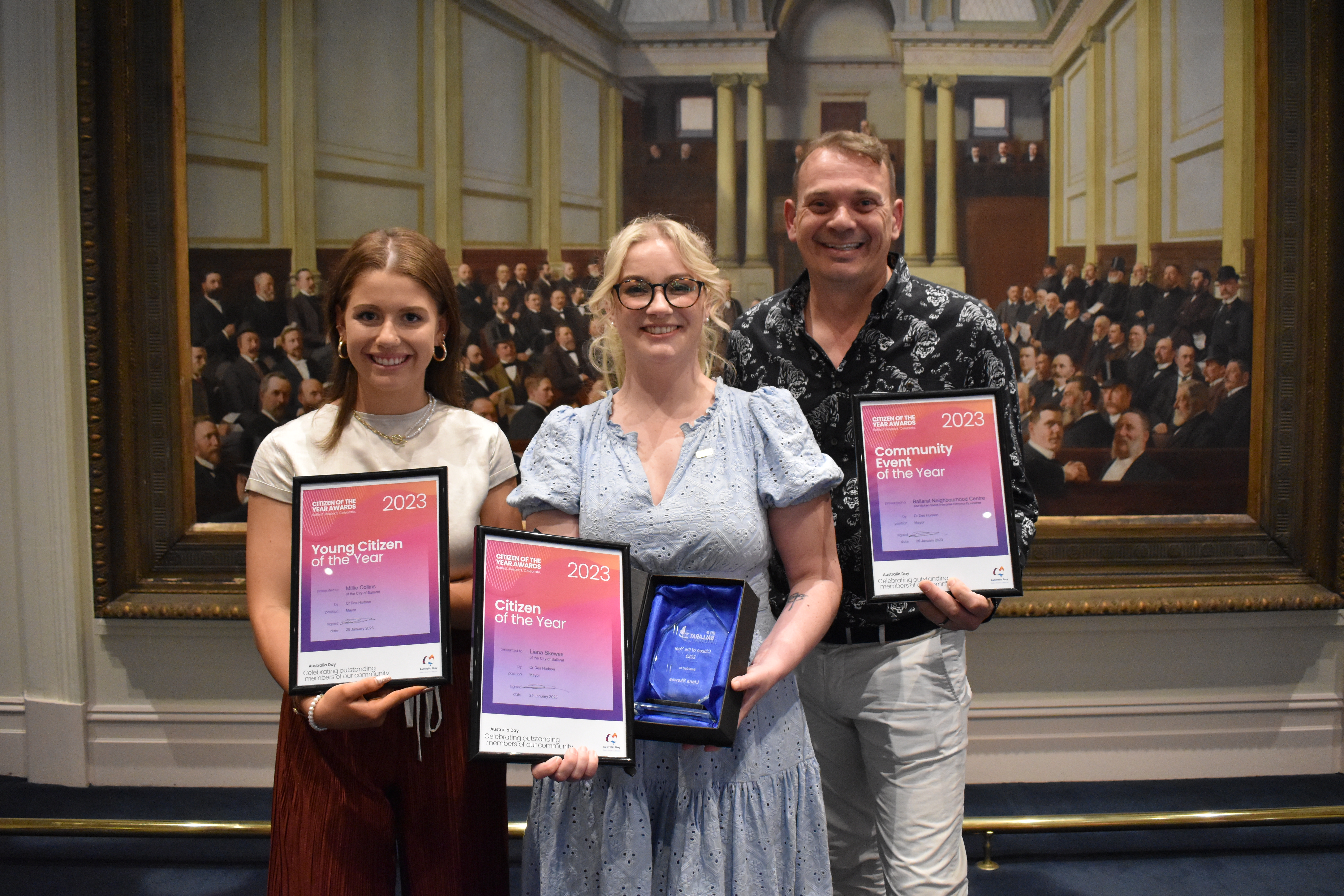 Young Citizen of the Year Millie Collins, Ballarat Citizen of the Year Liana Skewes and David Bending of Ballarat Neighbourhood Centre stand in front of a painting in Ballarat Town Hall. 