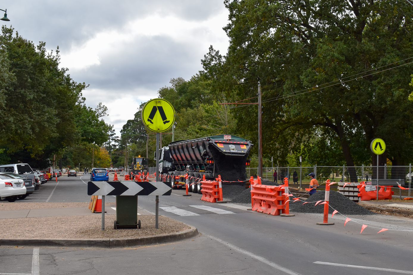 Road works occurring on a tree-lined street.