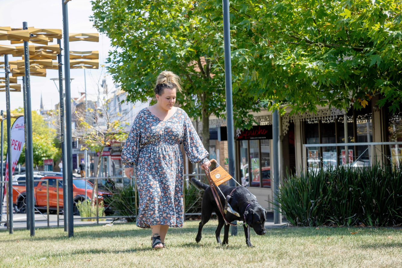 Heidi Biggin walks on a patch of grass with her guide dog Freya.
