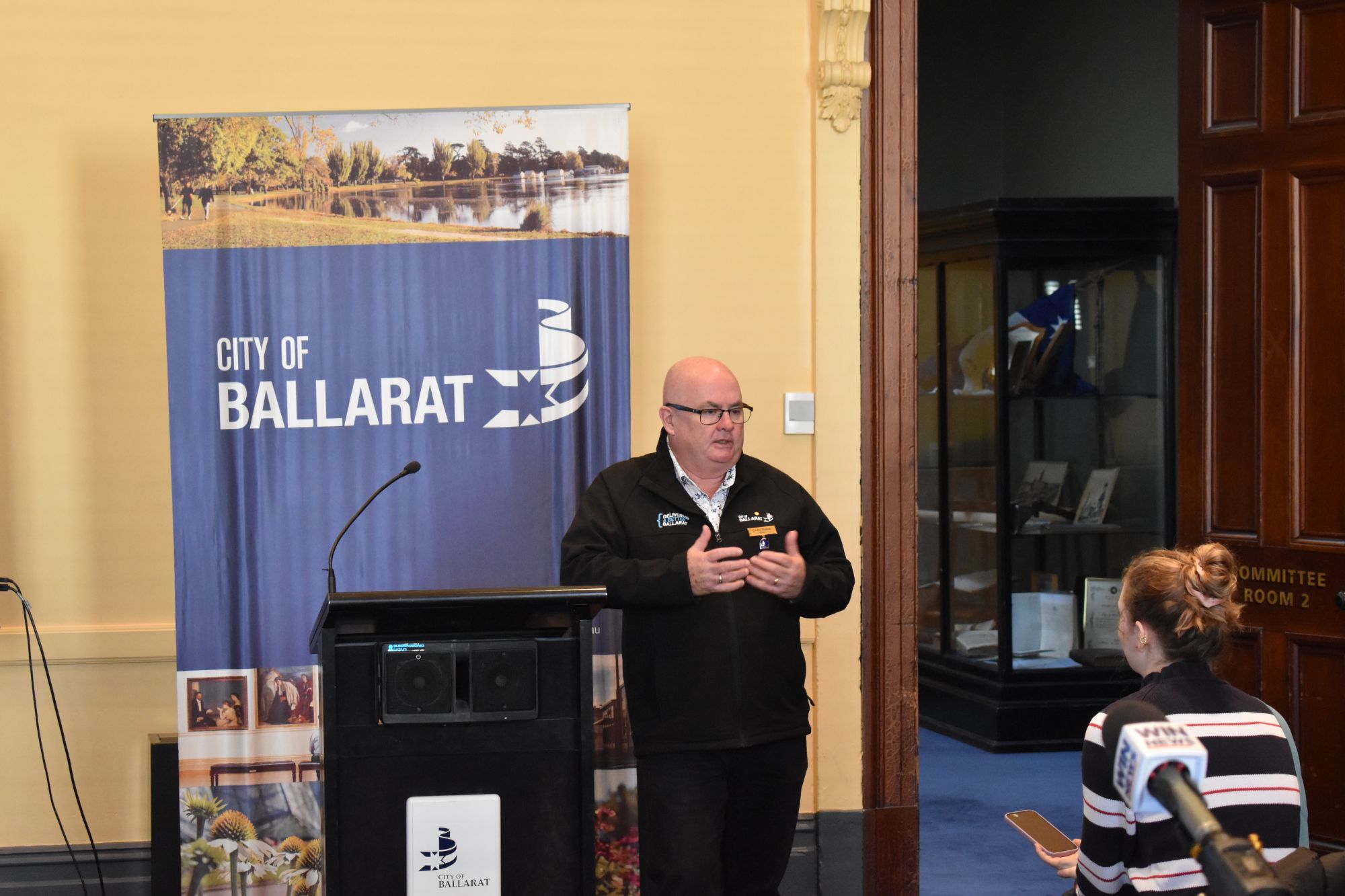 City of Ballarat Mayor Cr Des Hudson stands next to a lectern. 