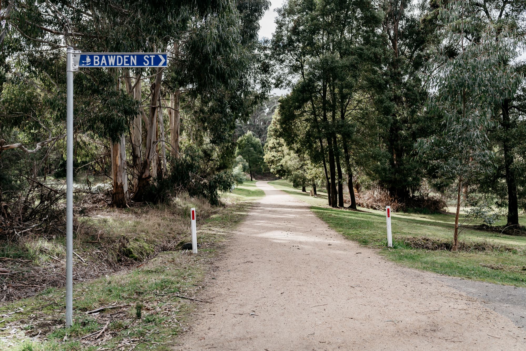A blue sign on the left says 'Bawden Street'. Next two it there is a tree-lined track.