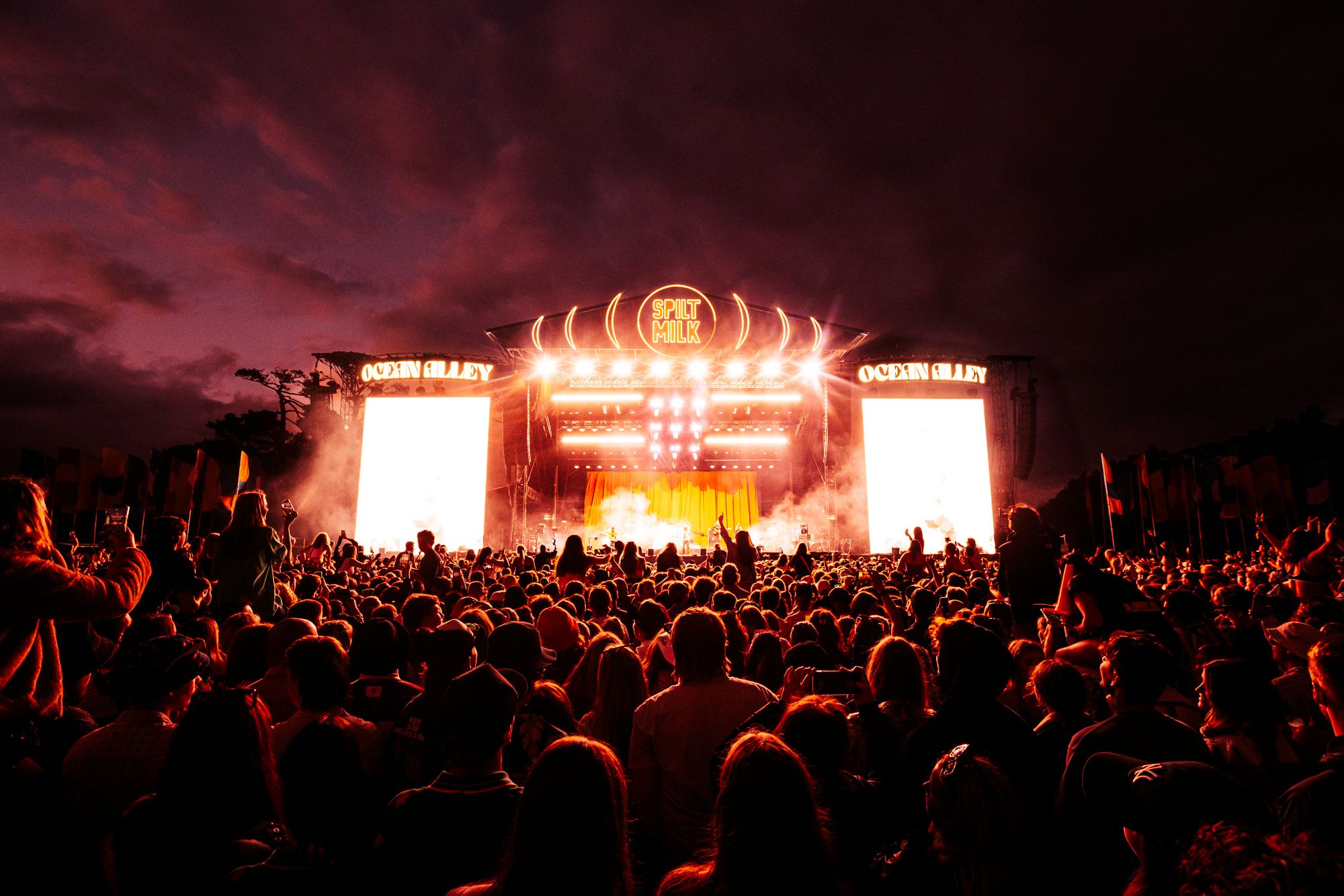 The Spilt Milk stage is lit up behind a dark night sky. 