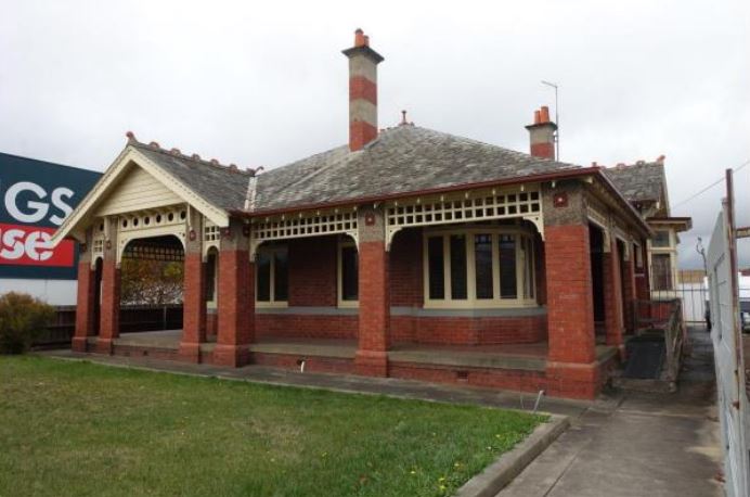 An image of Osborne House, a federation-era villa, which is located next to Bunnings. The red-brick house has a green lawn in front of it and you can see part of the 'Bunnings' sign to the left of the house.