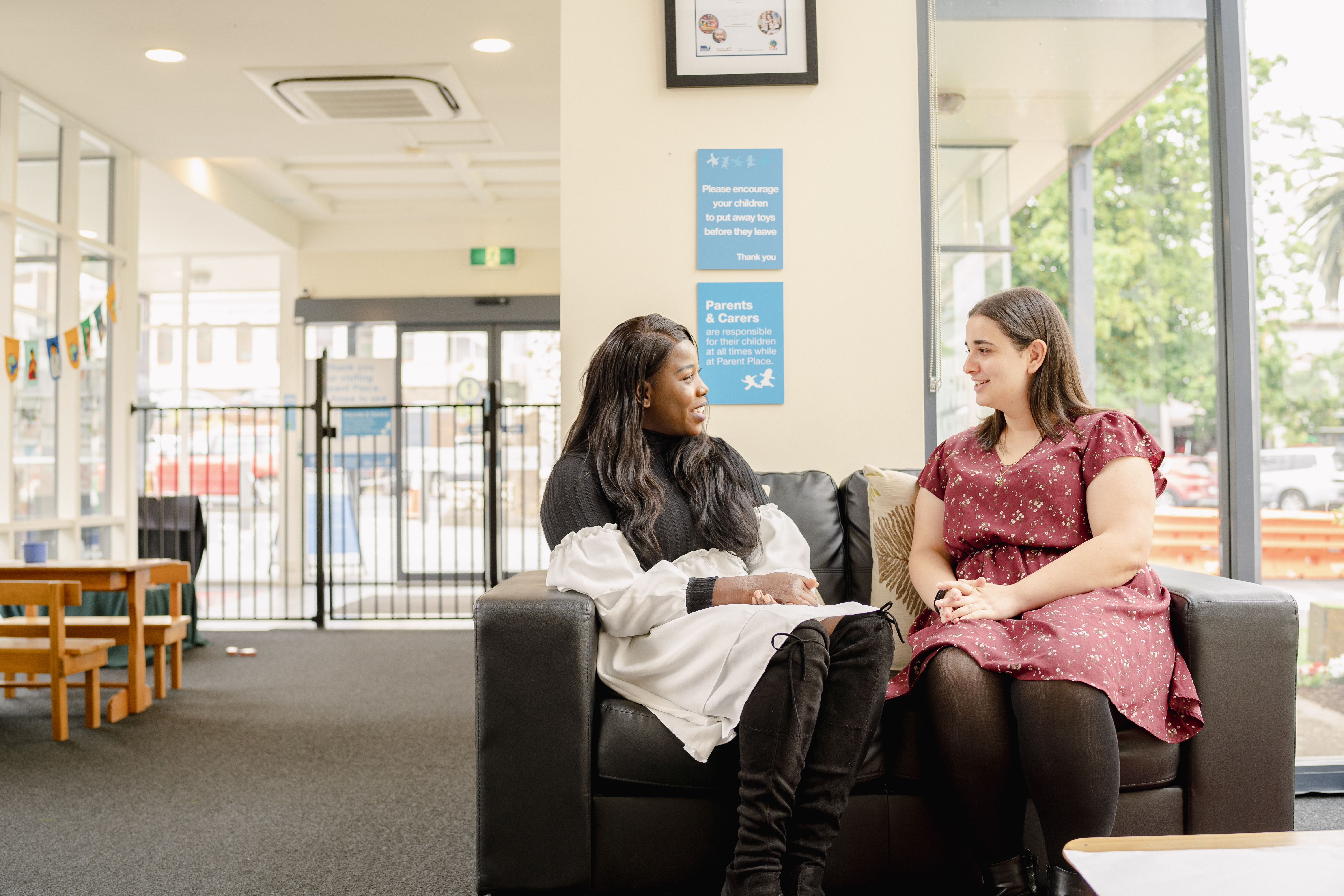 two women chat sitting on a couch