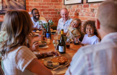 Generic photo group of people around a table sharing food and conversation