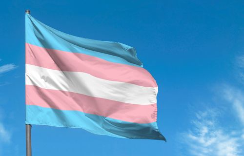 Transgender flag flying in a blue sky