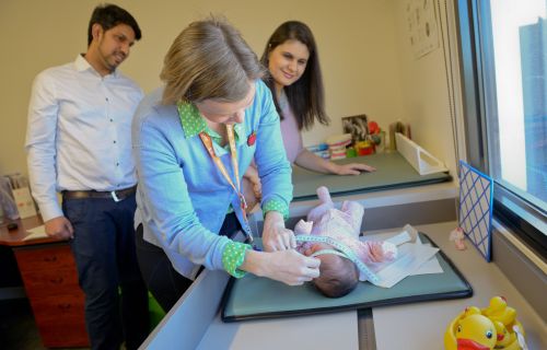 A maternal and child health nurse attends to an infant with parents nearby