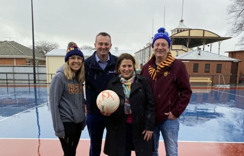 netballer, Mayor, Local Minister and President of Redan Football Club stand with a netball in front of the brand new netball courts and lights at City Oval