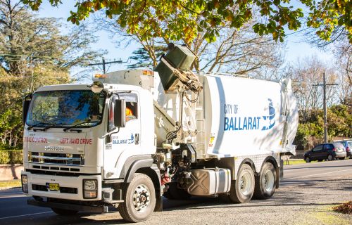 A waste truck lifts a bin, preparing to empty it. 