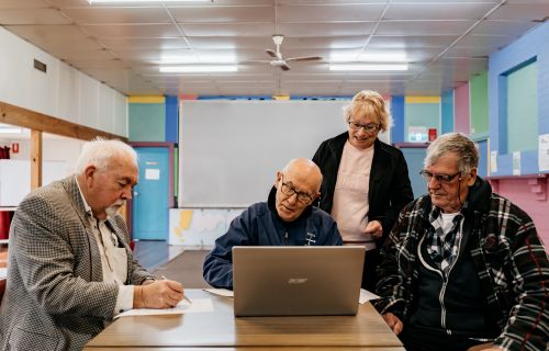 Generic photo group of people around a table working on a computer