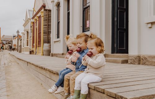 Generic photo group of children sitting on a step eating toffee apples
