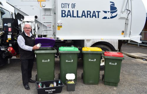 Cr Des Hudson with 4 bins in front of a city of ballarat rubbish truck