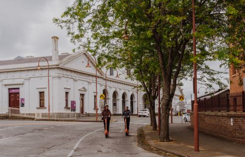 Generic image of two people using e-scooters Ballarat Train Station