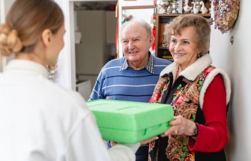 Elderly couple receiving a meal at doorstep