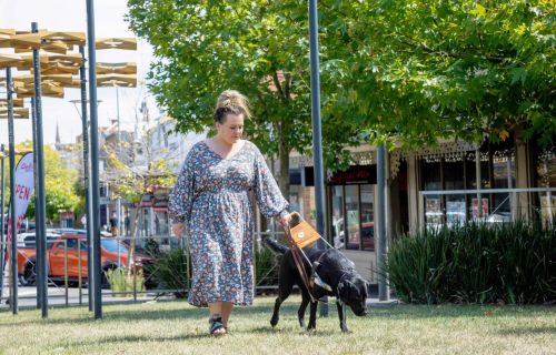 Heidi Biggin walks on a patch of grass with her guide dog Freya. 