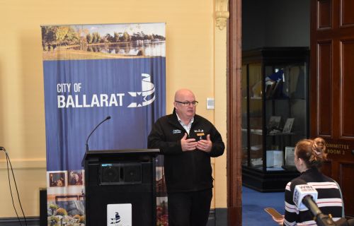 City of Ballarat Mayor Cr Des Hudson stands next to a lectern. 