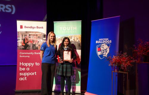 Two girls standing in front of promotional banners accepting an award