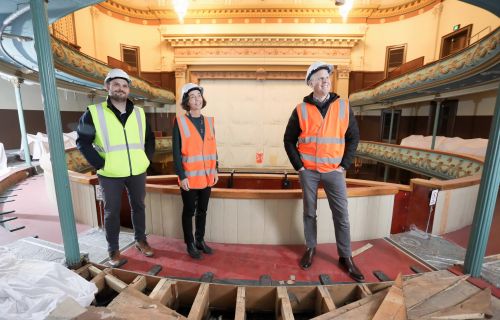 Three people in high-vis vests stand on the second tier of the Her Maj construction site