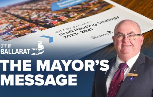Text with The Mayor's Message with an image of Mayor Cr Des Hudson in front of the Public Housing Strategy