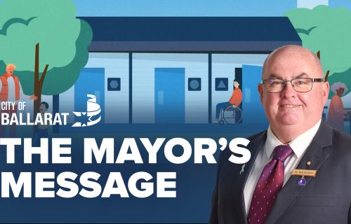 Text with The Mayor's Message with an image of Mayor Cr Des Hudson in front of public toilet image