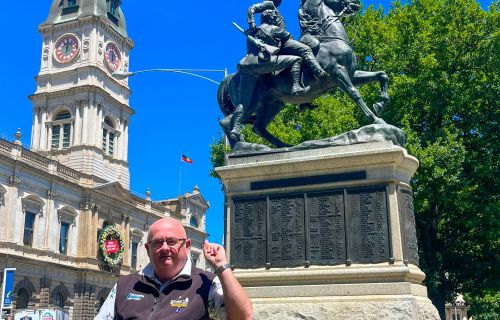 Mayor Cr Des Hudson standing in front of the Boer War Memorial Statue in Sturt Street with Town Hall in the background.