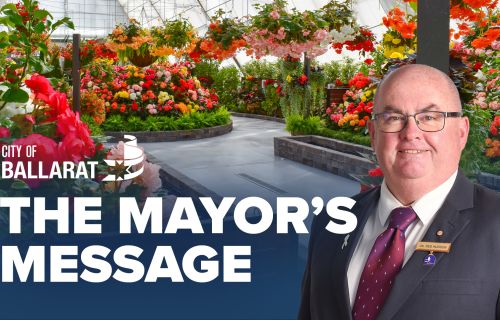 Text with The Mayor's Message with an image of Mayor Cr Des Hudson in front of the begonia display at the Botanical Gardens
