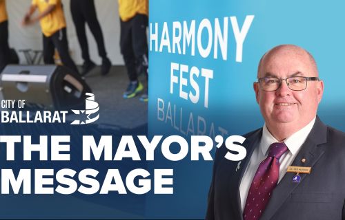 Text with The Mayor's Message with an image of Mayor Cr Des Hudson in front of the Harmony Fest stage