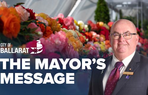 Text with The Mayor's Message with an image of Mayor Cr Des Hudson in front of a begonia display