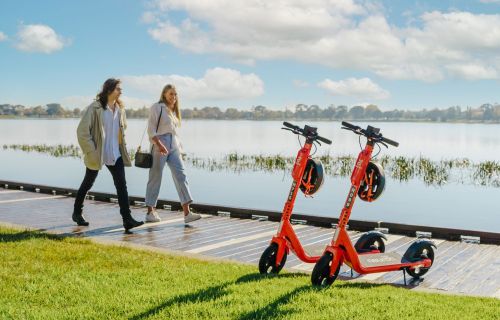 people walking by the lake with scooters parked on lakes edge