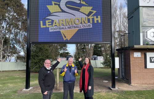 City of Ballarat Mayor Cr Des Hudson, Learmonth Football Netball Club life member Paul Ryan, and Member for Ripon Martha Haylett underneath the new scoreboard.