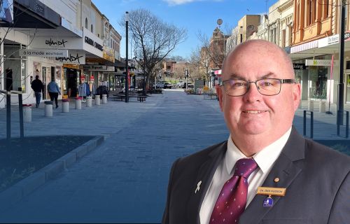 An image of Mayor Cr Des Hudson in front of the Bridge Mall redevelopment