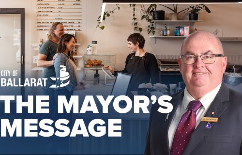 Text with The Mayor's Message with an image of Mayor Cr Des Hudson in front of a local cafe.