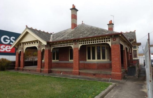 An image of Osborne House, a federation-era villa, which is located next to Bunnings. The red-brick house has a green lawn in front of it and you can see part of the 'Bunnings' sign to the left of the house.