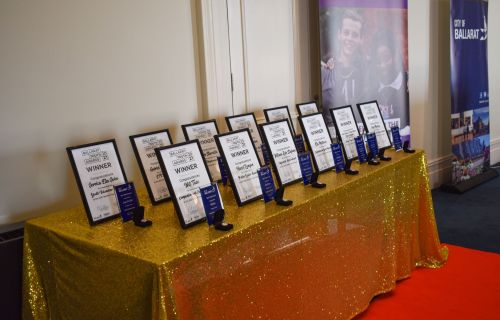 Award certificates lined up on a gold table