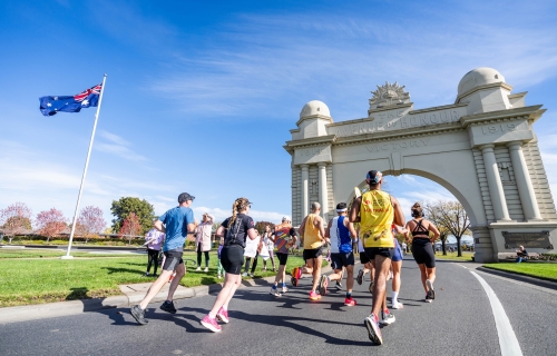 Runners in the marathon running towards the arch of victory