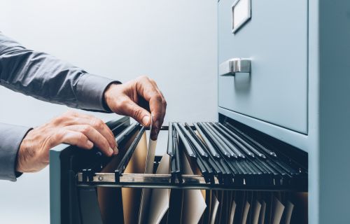 Hands flicking through a filing cabinet