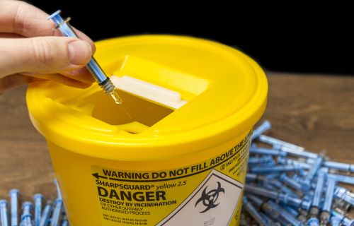 Needles being put into a sharps bin 