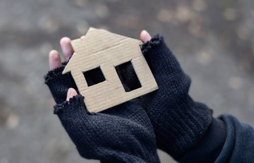 Hands holding a small cardboard house