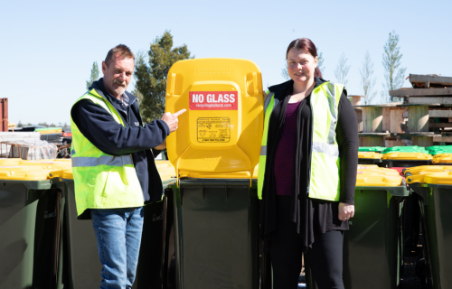 Andrew Clarke and Lisa Forssman standing in front of house hold recycling bins.