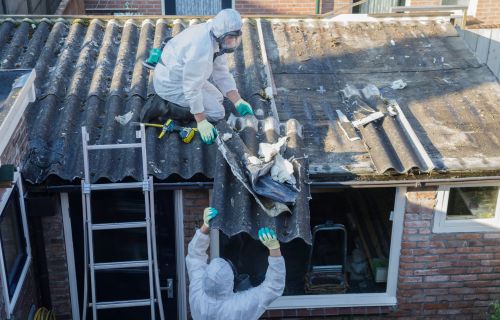 Image of professional asbestos removal: people in protective suits are removing asbestos cement corrugated roofing